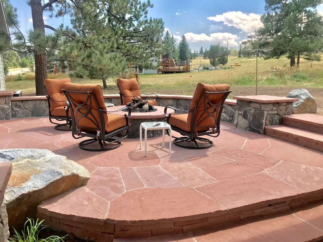 Cozy outdoor seating area with swivel chairs and stone patio overlooking lush landscape.