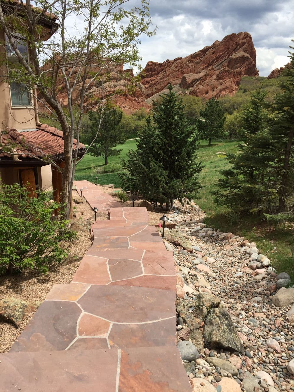 Stone pathway leading to a lush green landscape with rocky hills in the background.